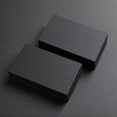 Two sleek black business cards elegantly placed on a textured gray surface, showcasing minimalist design and subtle embossed lettering for a professional look.