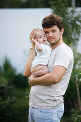 Young father cuddling newborn baby in summer garden. Dad hugging son, sweet infant outdoors. Happy fathers day! Adoption, love and family concept