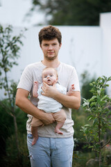 Young father holding newborn baby in summer garden. Dad hugging son and having fun with sweet infant outdoors. Happy fathers day! Adoption, love and family concept