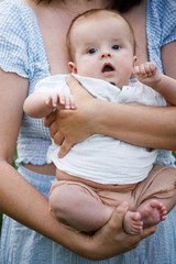 Close up of mother holding newborn baby in summer garden. Sweet infant son in mom hands outdoors. Happy mothers day! Adoption, love and family concept