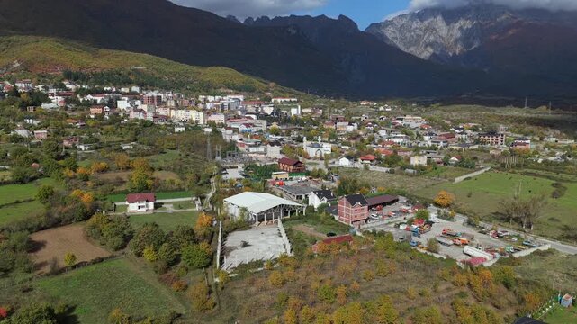 Aerial video of Bajram Curri, showing homes, farmland and the town center set against the steep forested slopes and rugged peaks of the Albanian Alps. 