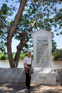 Senior woman next to the Bolivar Stone inscribed with names and dates that narrate the route of freedom followed by Bolivar at the colonial Heritage Town of Santa Cruz de Mompox in Colombia.