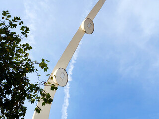 White structure with two round lights on top of it. sky is blue and clear. modern street lighting
