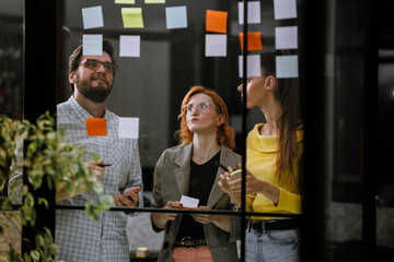 Team members brainstorming ideas during a creative meeting in a modern office space with colorful sticky notes on the wall