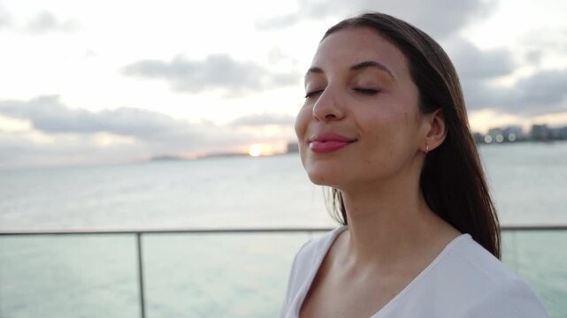 Peaceful young woman enjoying sea ​​breeze at sunset in Maceio promenade, Brazil. Slow motion.