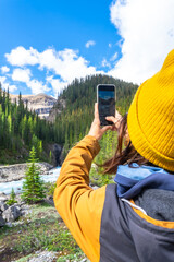 Hiker taking pictures of scenic waterfall along hiking trail in canadian rockies