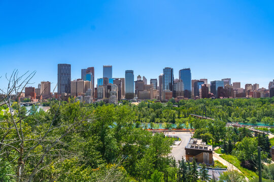 Calgary skyline rising above lush green park and river on sunny day