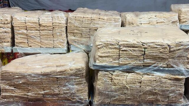 stacks of traditional indian gajak sweets packed in transparent plastic at a street market
