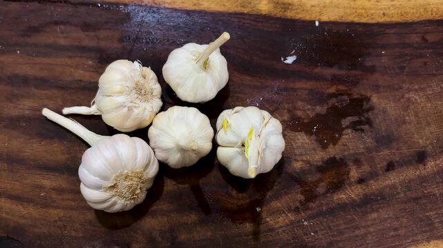 fresh whole garlic bulbs arranged on wooden cutting board top view