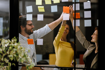 Team members collaborating on brainstorming session using sticky notes in modern office space during afternoon hours