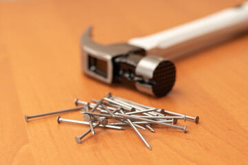 Hammer and pile of metal nails on orange background, tools for construction and repair work, carpentry concept