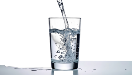 Water being poured into a clear glass against a stark black background.