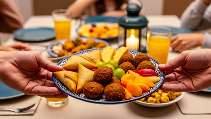Hands sharing a plate of food for Ramadan holiday dinner celebration  