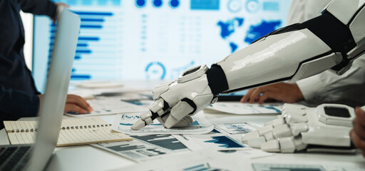 A futuristic work scene featuring a robotic arm collaborating with human colleagues in a data analysis meeting, showcasing advanced technology in a professional setting.Noogenesis