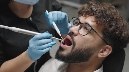 Dentist performs teeth cleaning on patient in clinic using tools and techniques for oral health
