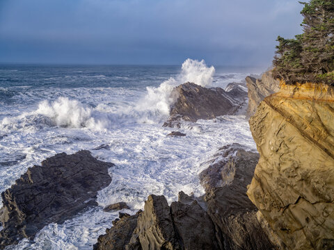 Waves crash on rocks below sandstone cliffs on the Pacific coast near Coos Bay, Oregon, USA