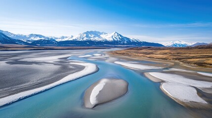 An aerial perspective of a braided river system running through snow-capped wilderness