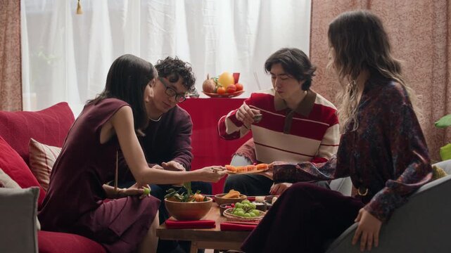 Stab shot of four Asian friends communicating while sitting at festive table during Tet celebration at home