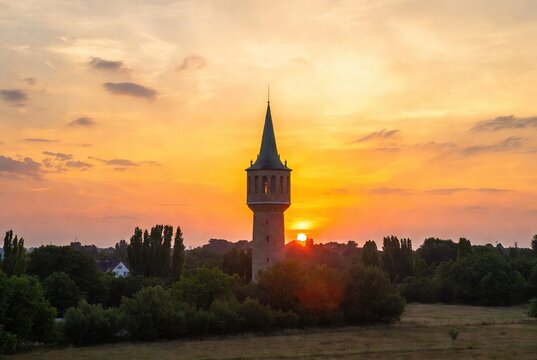 Tall stone tower silhouetted against a beautiful orange and yellow sunset