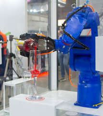 Robotic manipulators. Robot pouring liquid drink from bottle into glass. Industrial robot. Robot arm hand. Industrial manipulators for variety welding, material handling, palletizing. Robotization