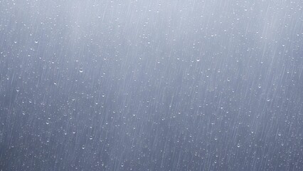 Close-up view of falling rain or snow against a blurred grey background, creating a serene and atmospheric scene.