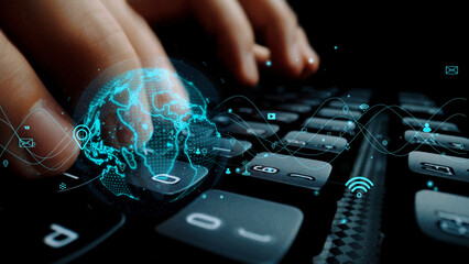 Close-up view of hands typing on a keyboard, featuring a digital globe graphic. This image symbolizes global connectivity and technological advancement in the modern world. Xenic