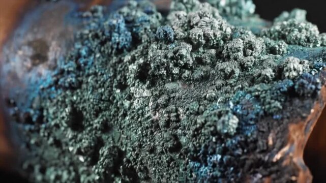 Corroded copper pipe with green and blue oxidation, close up.