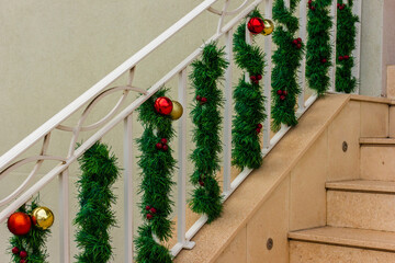 Festive Christmas Garlands Wrapped Around White Staircase Railing with Red and Gold Ornaments