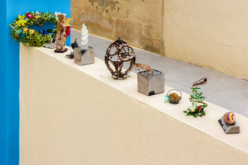 Colorful Handmade Ornaments and Trinkets Displayed on Table Outside a Sunny Building