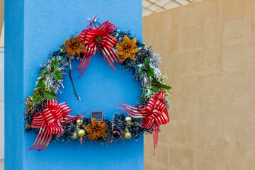 Festive Christmas Wreath Decoration On Bright Blue Pillar With Red Ribbons And Gold Ornaments