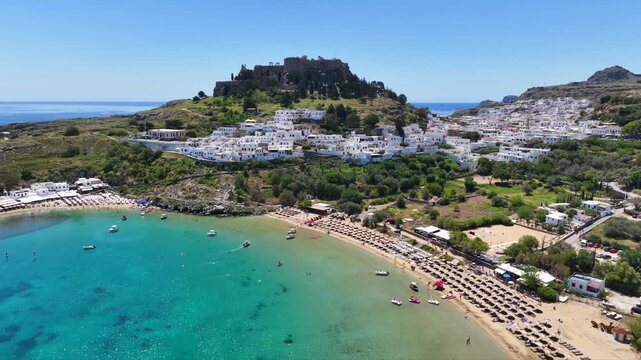 Aerial drone cinematic video of paradise organized main beach of Lindos with amazing turquoise waters, Rhodes island, Dodecanese, Greece