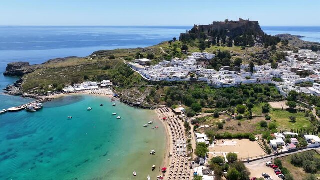 Aerial drone cinematic video of paradise organized main beach of Lindos with amazing turquoise waters, Rhodes island, Dodecanese, Greece
