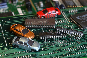 Toy cars on electronic board and microchip. The shortage of microchips and semiconductors creates a shortage of new cars. Conceptual image for semiconductor shortage