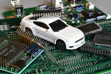 Toy cars on electronic board and microchip. The shortage of microchips and semiconductors creates a shortage of new cars. Conceptual image for semiconductor shortage