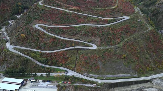Aerial video of winding mountain switchbacks near Fierz&euml;, surrounded by rugged autumn slopes. 
