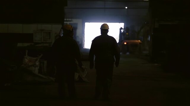 Factory Workers in Silhouette Moving Through Dark Industrial Corridor, Shift Ending - 4K