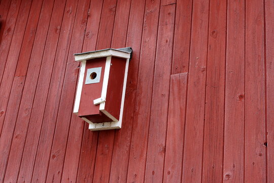 Red and white birdhouse on a wooden wall. Typical Swedish.