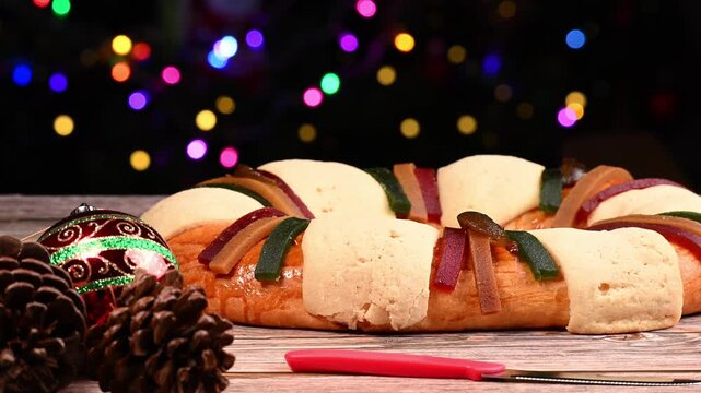 Seasonal food, Mexican Rosca de Reyes, festive bread decorated with crystallized fruit and sugar, with Christmas lights in the background