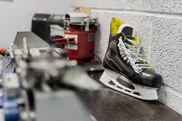 Ice hockey skate waiting for sharpening next to professional skate sharpening equipment, illustrating team level sports gear maintenance and workshop operations