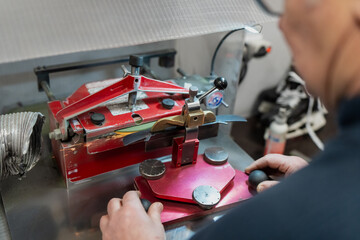 Hockey equipment manager operating professional automatic skate sharpening machine in workshop, highlighting precision blade maintenance for elite ice hockey teams