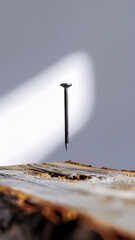 A Floating Nail Above Weathered Wood Under Soft Studio Light in a Conceptual Minimalist Scene