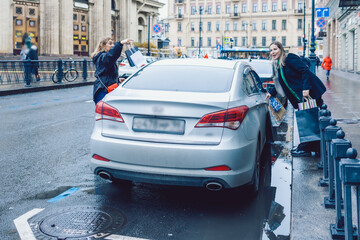 Two women hail taxi after leaving store with shopping bags. High quality photo