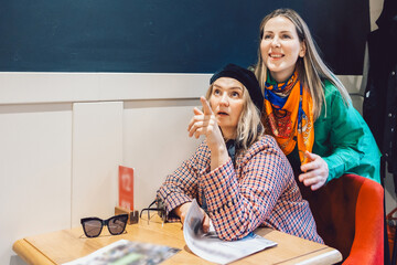 Two beautiful girls met in cafe, talked and read newspapers. High quality photo