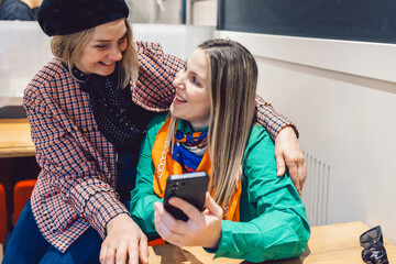 Two beautiful women met in cafe and looked at messages on their phones. High quality photo