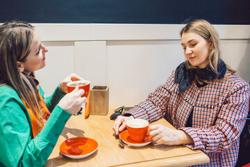 Two women met and are sitting in a cafe drinking coffee and talking. High quality photo