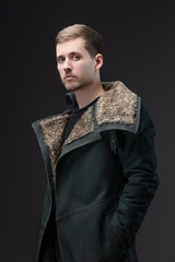 Gloomy future fashion: young man in face-concealing coat, cyberpunk studio portrait.