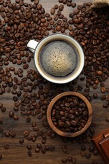 Fototapeta premium Aromatic coffee in cup and beans on wooden table, flat lay
