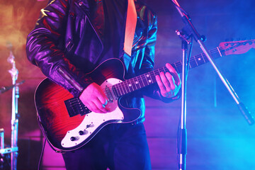 Obraz premium Man playing electric guitar on stage with smoke, closeup