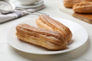 Delicious eclairs served on white table, closeup