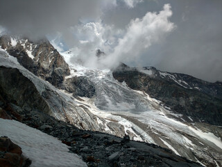 Widok na lodowiec i szczyty Alp podczas pochmurnej pogody, nastrojowe tło górskie © W Podróży do Chmur